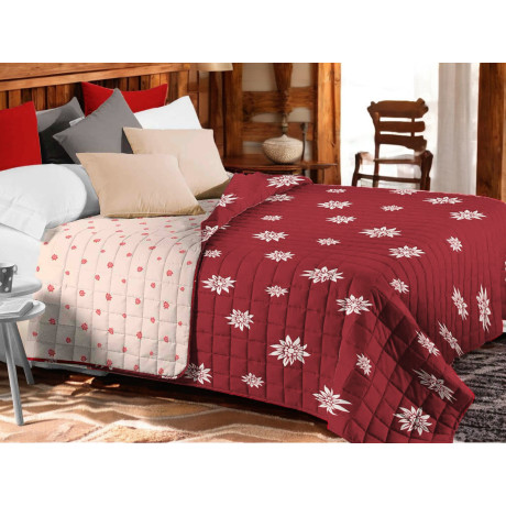 Couvre-lit matelassé Edelweiss rouge avec fleurs blanches sur lit rustique