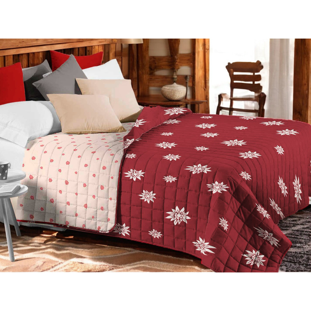 Couvre-lit matelassé Edelweiss rouge avec fleurs blanches sur lit rustique